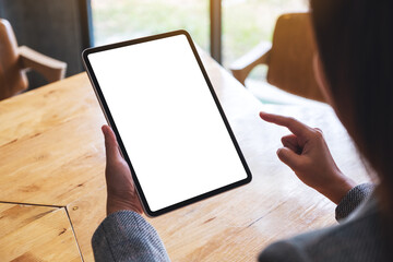 Mockup image of a woman holding and pointing finger at digital tablet with blank white desktop screen