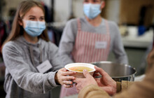 Volunteers Serving Hot Soup For Homeless In Community Charity Donation Center, Coronavirus Concept.