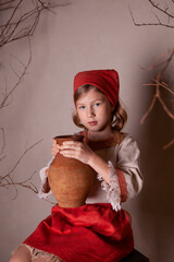 Wall Mural - little girl in a light linen shirt and a red scarf in a rustic style