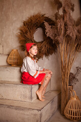 Wall Mural - little girl in a light linen shirt and a red scarf in a rustic style