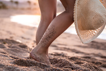 Wall Mural - Feet of a woman in the sand with a hat