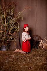 Wall Mural - little girl in a light linen shirt and a red scarf in a rustic style