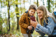 © djoronimo - Happy mother and son are hiking in forest. They are using maps on smart phone.