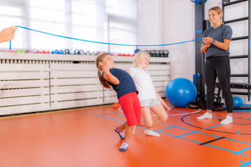 Limbo or laser game for children, little girls having fun in a physical activity class