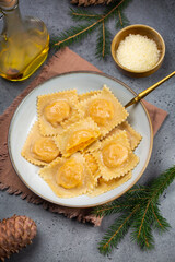 Poster - Italian  Christmas eve dinner: tortelli or ravioli stuffed with pumpkin and parmesan cheese. Grey background. Copy space. christmas decoration. Vertical image.