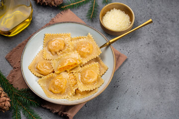 Canvas Print - Italian  Christmas eve dinner: tortelli or ravioli stuffed with pumpkin and parmesan cheese. Grey table. Copy space. christmas decoration. Vertical image.