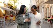 © VAKSMANV - Mixed-races females walking the street, talking and watching video on phone. Multi ethnic young women chatting and using smartphone. Cheerful Asian and African American girls gossiping. Gossips.
