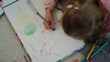 © stockbusters - Unknown girl lying floor with colored pencils. Creative kid drawing picture home