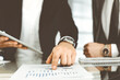 © Iryna - Business people using tablet computer while working together in modern office. Unknown businessman sitting at the desk with his colleague or partner. Teamwork and partnership concept