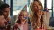 © stockbusters - Mom dad kids celebrating birthday online. Happy family having fun party blowers.