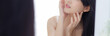 © N_studio - Beautiful young asian woman look at mirror of checking face with skin care and cosmetic for hygiene, beauty girl happy clean facial with cream or lotion and for health, banner website.