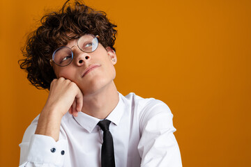 Wall Mural - Pensive young man student wearing glasses isolated