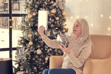 Senior Woman Talking With Family During Online Call . Happy Grandmothers During Video Conference Celebrating Winter Holidays. Soft Focus, Warm Tones