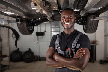 Wall Mural - portrait of positive afro american auto mechanic in uniform posing after work, he is keen on repairing cars, automobiles.