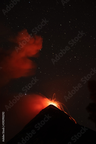 Smoke glows red as the volcano erupts hot molten lava.