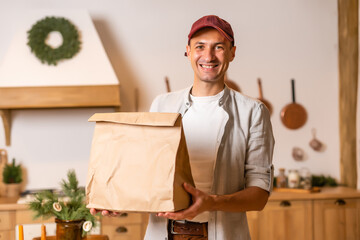 Canvas Print - a delivery man with a package of food stands in a Christmas interior