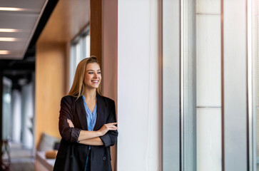 Smiling businesswoman standing in office and looking out of window
