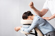 © LIGHTFIELD STUDIOS - Side view of masseur massaging woman back with elbow, sitting on massage chair on white background