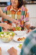 © DragonImages - Housewife putting portion of vegetable salad in plate of her husband when they are having party at home