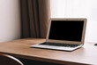 © uladzimirzuyeu - Laptop on work table in empty room or office. Off laptop with blank screen in the interior of the room.