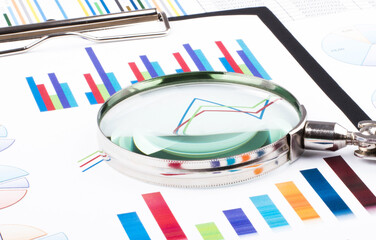 Magnifying glass lying on business charts and graphs. Business planning,accounting,analysis,financial planning and data Analysis concept.