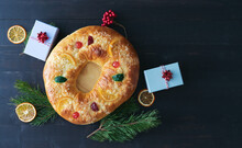 Kings Cake (Roscon De Reyes) With Christmas Decoration And Gift Boxes On A Dark Background. Copy Space. .