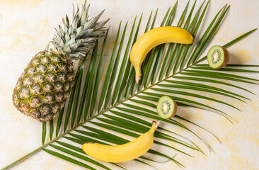  Pineapple,banana,kiwi and tropical palm leave on yellow background. Top view