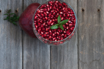 Wall Mural - Fresh pomegranate arils with mint leaves in a glass bowl on a weathered board table top.