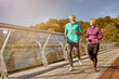© Kostiantyn - Stay in shape. Full length shot of active mature family couple in sportswear smiling at each other while jogging together on a sunny autumn day. Joyful senior couple doing sport outdoors