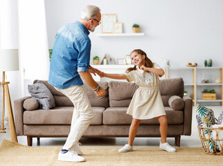 Grandfather dancing with granddaughter at home.