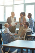 © Kostiantyn - Vertical shot of cheerful multiracial business people having a meeting in the modern office, discussing work and smiling