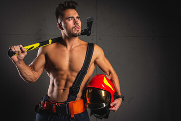 Fashionable portrait of a young man in fire equipment on a black studio background. Fireman in a dark uniform.