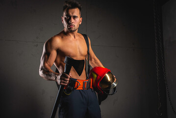 Wall Mural - Fashionable portrait of a young man in fire equipment on a black studio background. Fireman in a dark uniform.