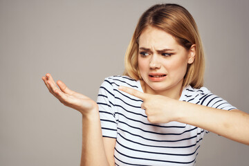 Wall Mural - A woman with a displeased expression is gesturing with her hands T-shirt gray background