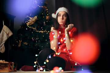 Stressed Woman Tangled in Fairy Lights under Christmas Tree