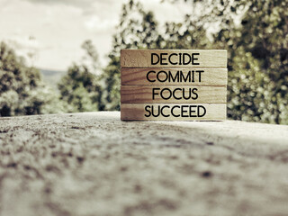 Wall Mural - Inspirational words of decide commit focus succeed on wooden blocks background. Stock photo.