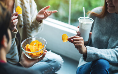 Wall Mural - Closeup image of friends talking, drinking and eating potato chips together