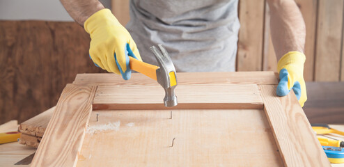 Wall Mural - Carpenter with hammer hitting nail on wooden plank.