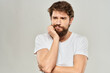 © SHOTPRIME STUDIO - A man in a white t-shirt with a beard emotions displeased facial expression light background