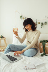 Woman raising wine glass celebrating christmas on video call