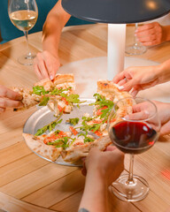 Friends hands with glasses of wine and pizza, close up.l Still life, group of people in a restaurant.