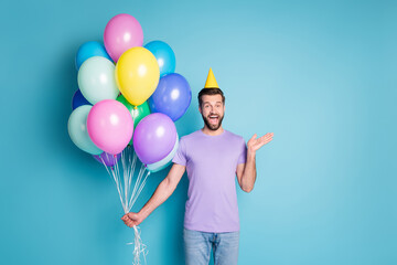 Wall Mural - Photo portrait of cheerful happy man keeping balloons wearing yellow headwear greeting on party isolated on bright blue color background