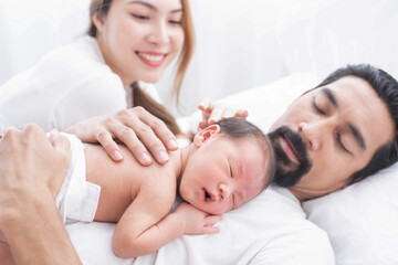 Wall Mural - smiling mother and father holding their newborn baby at home..portrait of happy family at home, young parents holding on hands little sweet newborn baby, love and happiness concept.