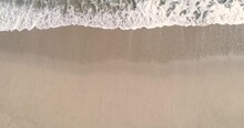 Static Top Down View Of Tropical Beach, Foamy Ocean Waves Washing Sand. Waves Hitting Sand Beach