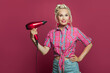 © millaf (Nemchinova) - Pin-up woman using hairdryer posing on pink background