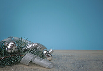 the christmas spruce sprig with silver decorations on wooden background with blue background