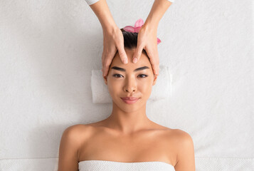 Wall Mural - Young asian woman enjoying anti-aging facial massage at spa salon