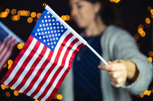 Young Woman Holding An American Flag With Sparkling Light Bokeh Background, Usa Concept