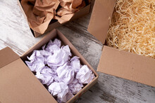 An Open Boxes With Filling Material Inside. Open Parcels On The Wooden Floor.
