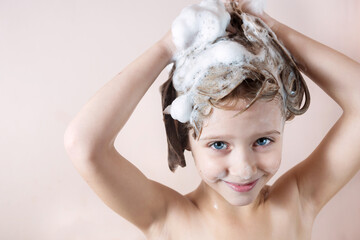 Wall Mural - adorable little girl with blue eyes washing her hair in the bathroom and laughs, foam on the head, l